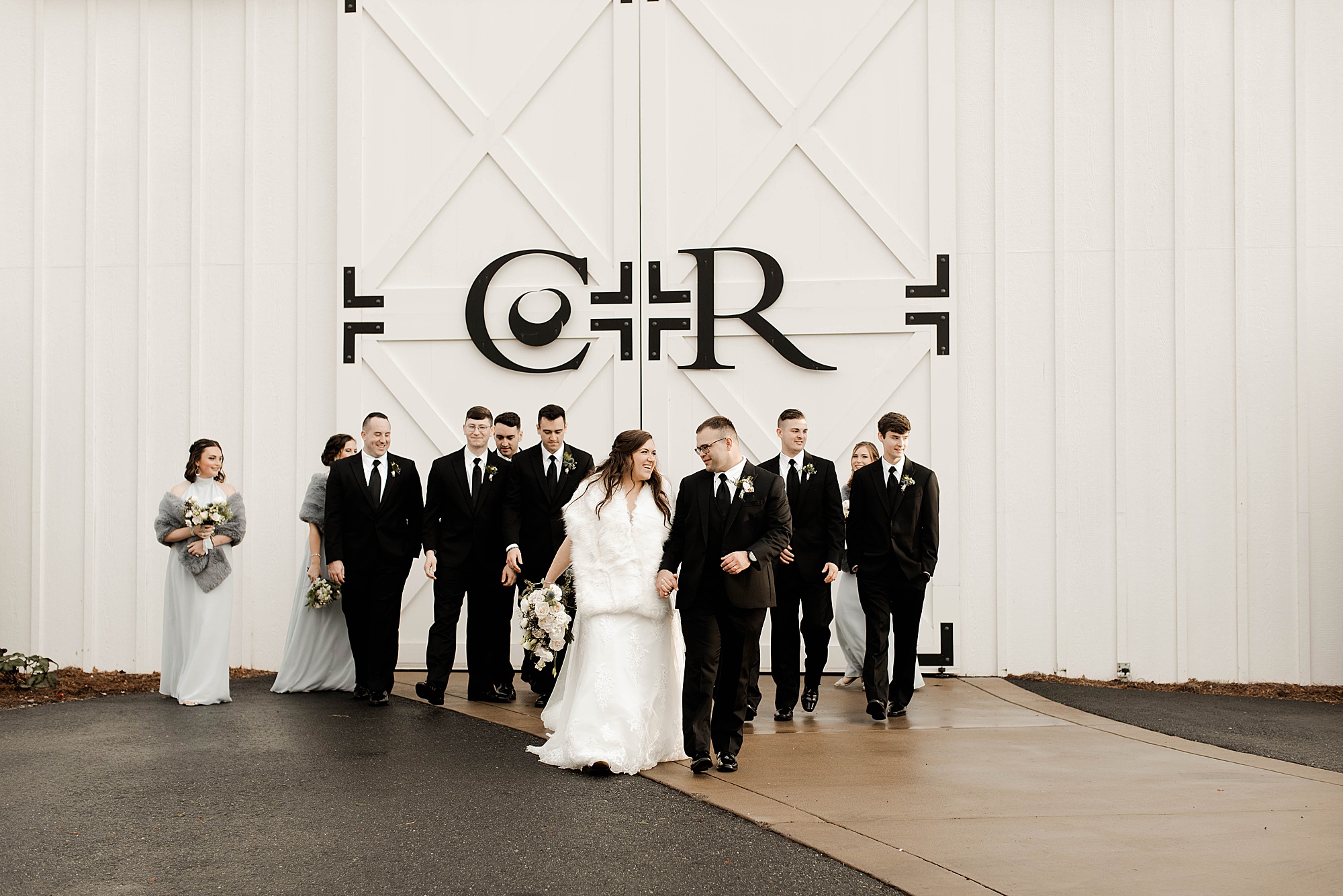 Bride and groom standing in front of Chestnut Ridge Wedding Venue with bridal party